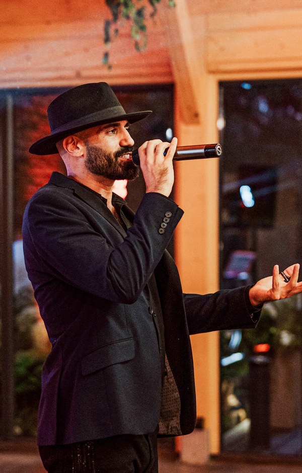 Sami Harb w czarnej fedorze śpiewa na wieczornym wydarzeniu